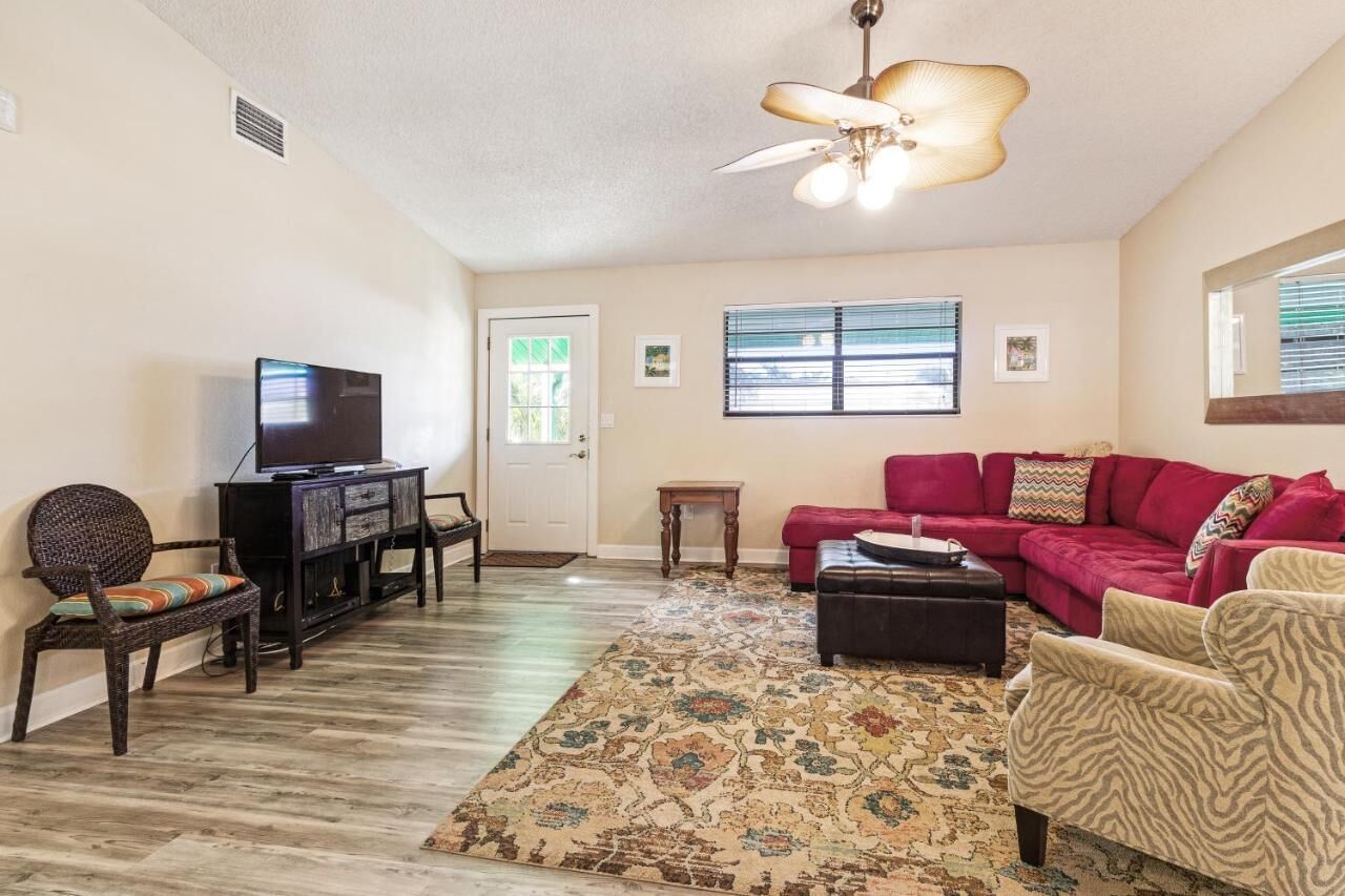 A living room with a television, a red sofa, a patterned rug, and a ceiling fan.