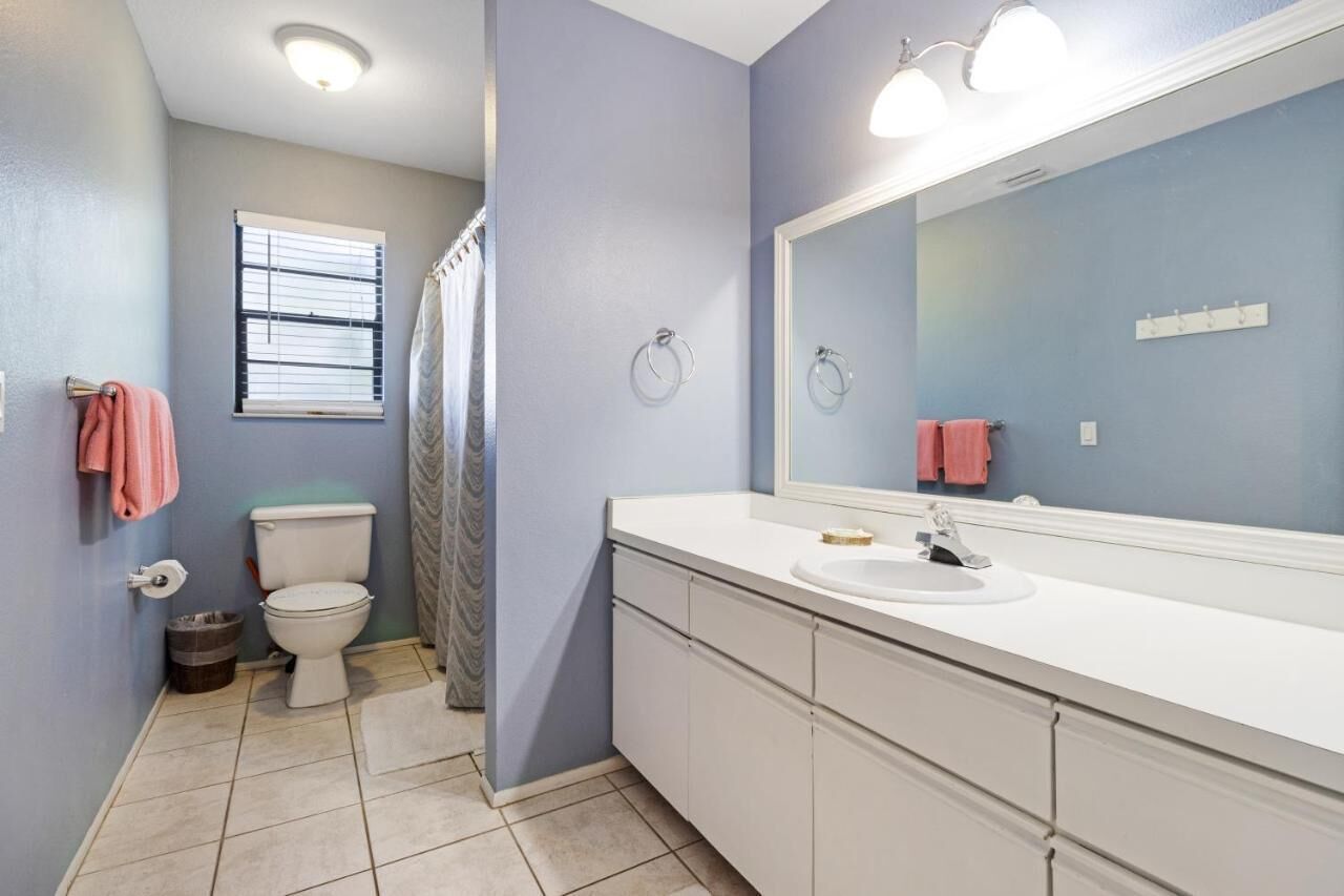 A bathroom with a toilet, sink, and mirror.