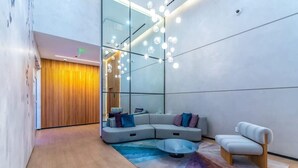 A modern living room with a sectional sofa, a round coffee table, and a minimalist chair. - Rooftop Pool & Ocean Views Near Bayside (Miami)