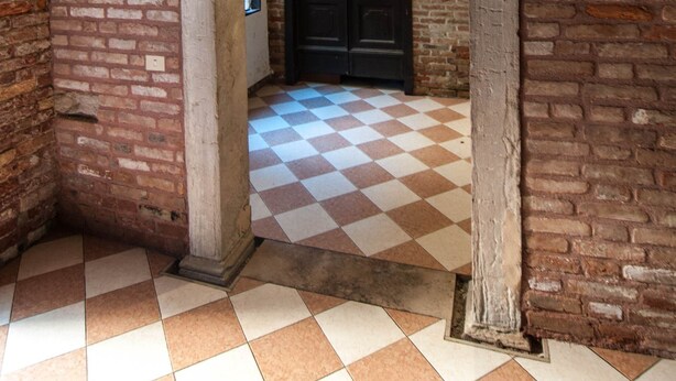 An arched doorway with a checkered floor, brick walls, and a dark door. - Luxury apartment, 100m from Piazza San Marco, Venice (Venezia)