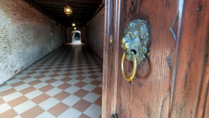 A hallway with a checkered floor and a wooden door with a metal knocker. - Luxury apartment, 100m from Piazza San Marco, Venice (Venezia)