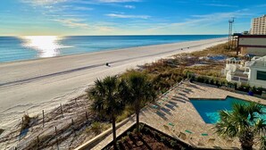 A beach view with a pool area, including a sunlit pool, lounge chairs, and a clear sky. - Pelican Walk 406 - BEST VIEW! Free Beach Chairs! (PANAMA CITY Beach)