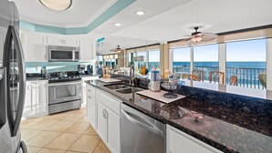 A modern kitchen with a large island, stainless steel appliances, and a view of the ocean. - Pelican Walk 406 - BEST VIEW! Free Beach Chairs! (PANAMA CITY Beach)