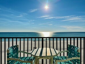 Ein Balkon mit Tisch und Stühlen, der auf einen Strand hinausgeht.