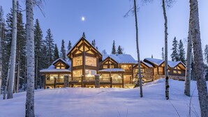 A log cabin with multiple levels and large windows, surrounded by snow-covered ground and trees. - BEARPAW MANOR- A Magnificent Ski-In/Ski-Out Mountain Village Chalet (Mountain Village)