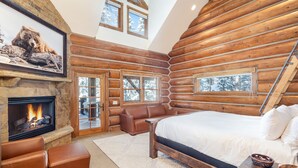 A log cabin interior with a fireplace, a large bed, a seating area, and wooden walls. - BEARPAW MANOR- A Magnificent Ski-In/Ski-Out Mountain Village Chalet (Mountain Village)