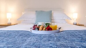 A neatly made bed with a tray of breakfast items including croissants, grapes, and a rose. - Little Hotsie, Southwold (Southwold)