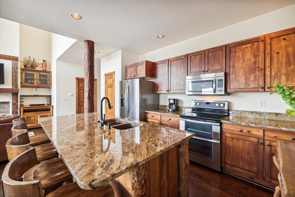 Enjoy cooking in this well-equipped kitchen with a large island, double oven, and stainless steel sink.