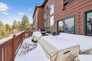 Enjoy outdoor cooking on the covered deck with a grill, surrounded by trees and a serene natural setting.