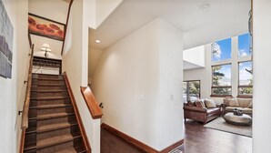 Un vaste espace de vie agrémenté d’un escalier en bois, d’une grande fenêtre offrant une vue agréable et d’un coin salon confortable.