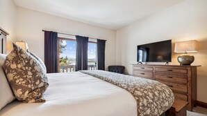 Une chambre d’hôtel avec un grand lit, une télévision, une commode et une vue sur l’extérieur.