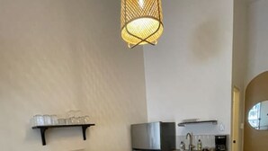 Cocina compacta con encimera de madera, lámpara colgante y suelo estampado.