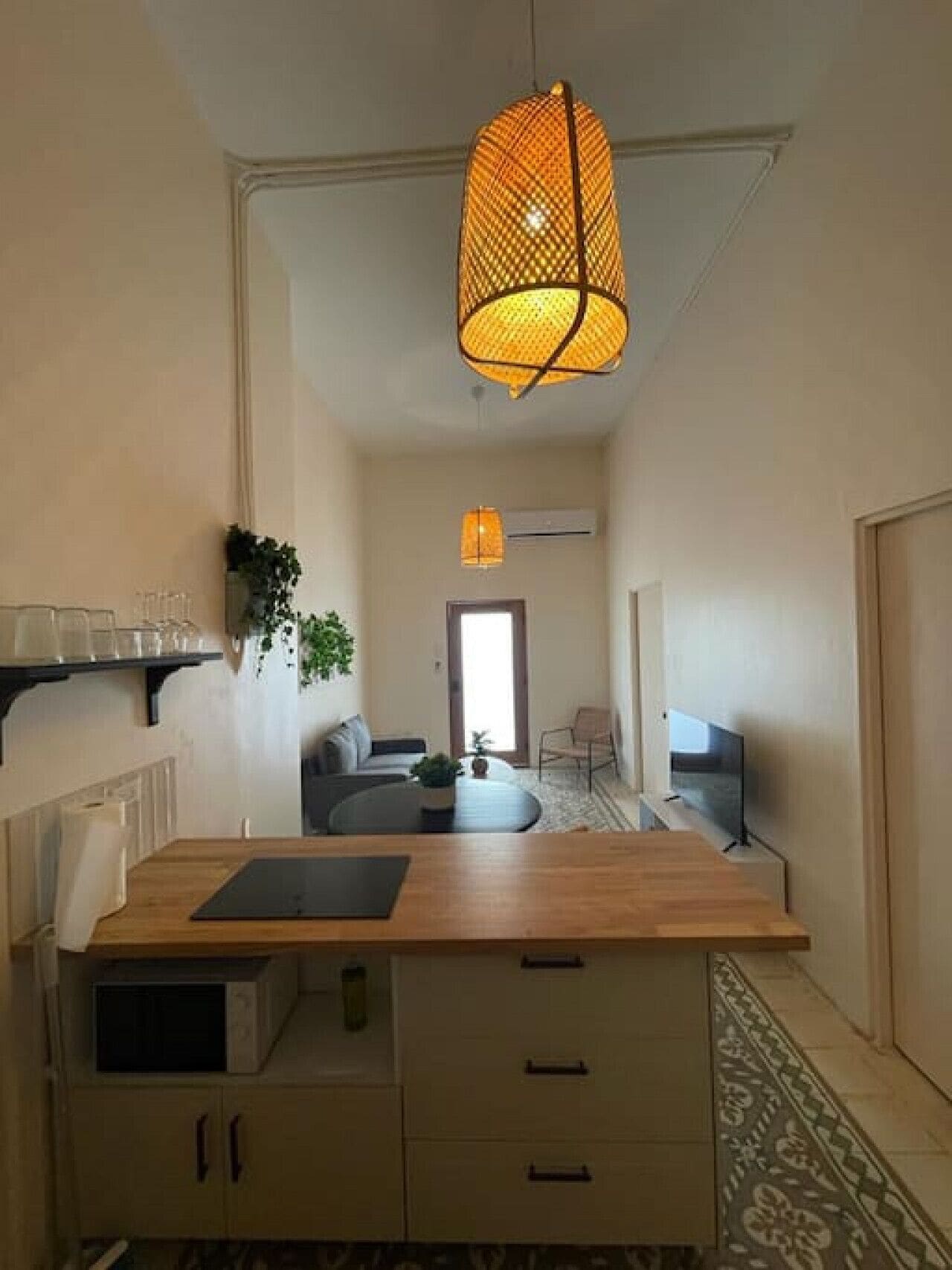 Una cocina moderna con encimera de madera, armarios empotrados y una lámpara colgante.