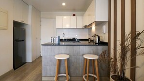 A modern kitchen with a central island, two stools, a refrigerator, and a potted plant. - w* | 1BR near Central Restaurant in Barranco (Barranco)