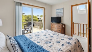 Een slaapkamer met een groot bed, een televisie, een dressoir en een balkon met uitzicht.