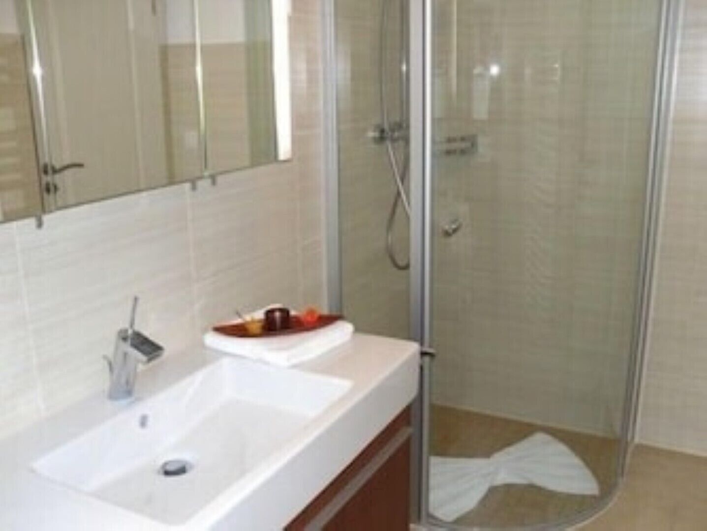 A bathroom with a white sink, a mirror, and a glass shower enclosure.