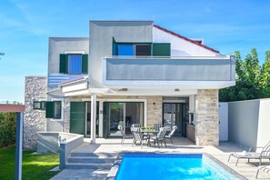 A modern two-story house with a swimming pool, outdoor seating, and a stone facade. - Villa Dana with Private Pool (Novalja)