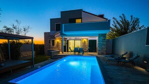 A modern two-story house with a swimming pool, outdoor seating, and a well-lit entrance. - Villa Dana with Private Pool (Novalja)