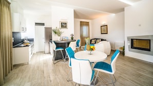 A modern kitchen with white cabinets, a dining area with blue chairs, and a fireplace. - Villa Dana with Private Pool (Novalja)