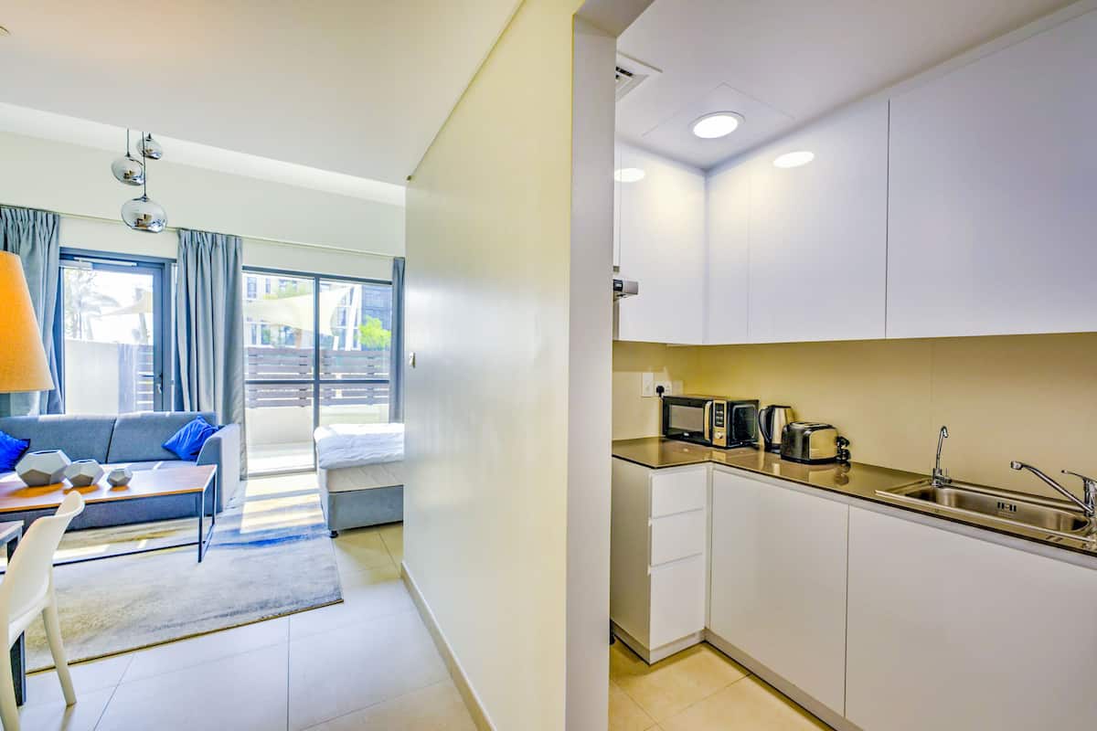 A compact living space with a kitchenette, a sofa, a dining table, and a window with curtains.