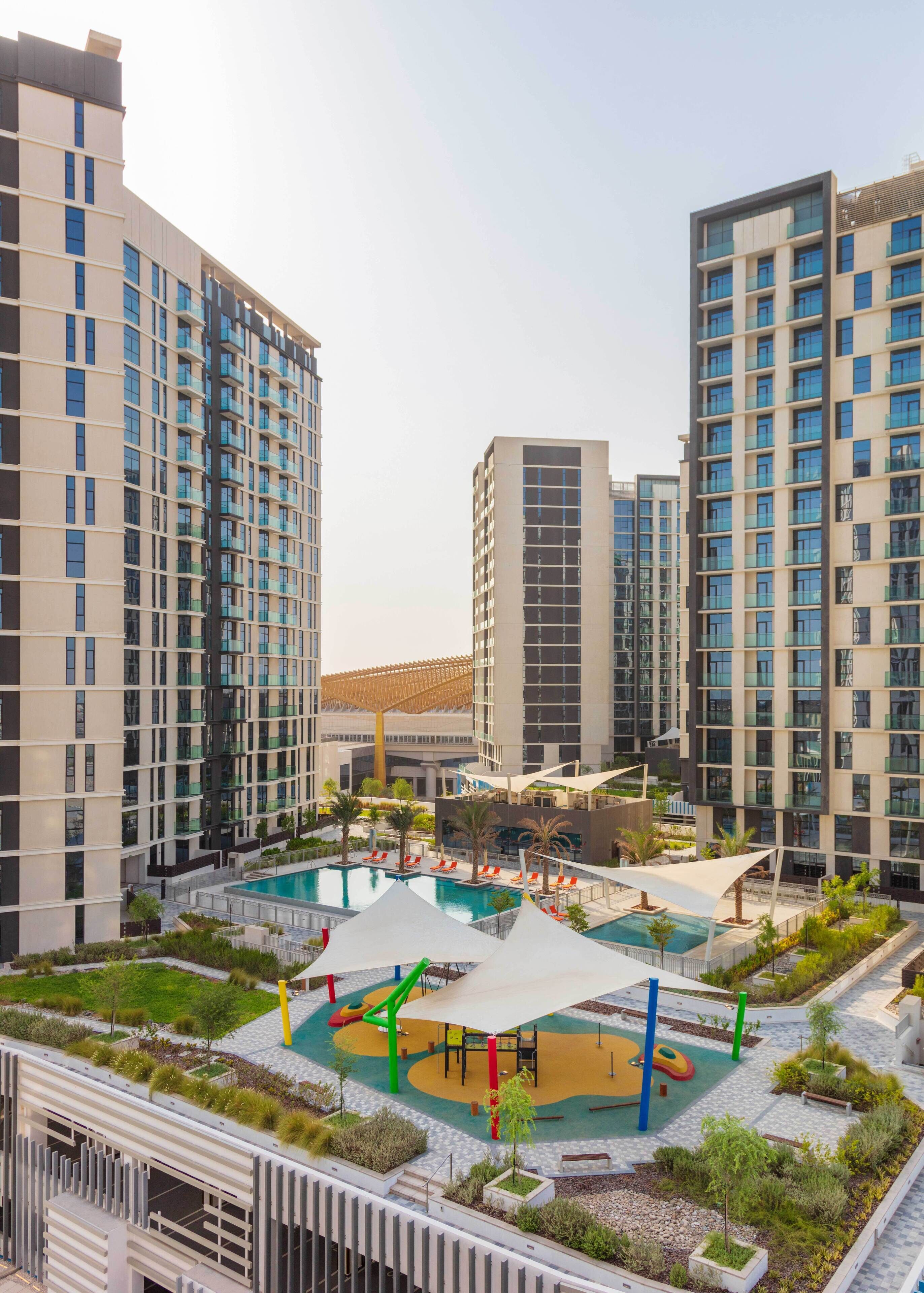 Un complexe résidentiel moderne comprenant plusieurs immeubles à étages, une cour intérieure avec une piscine et des espaces de détente en plein air.