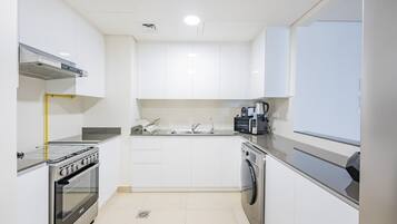 A modern kitchen with white cabinets, stainless steel appliances, a built-in oven, and a dishwasher.