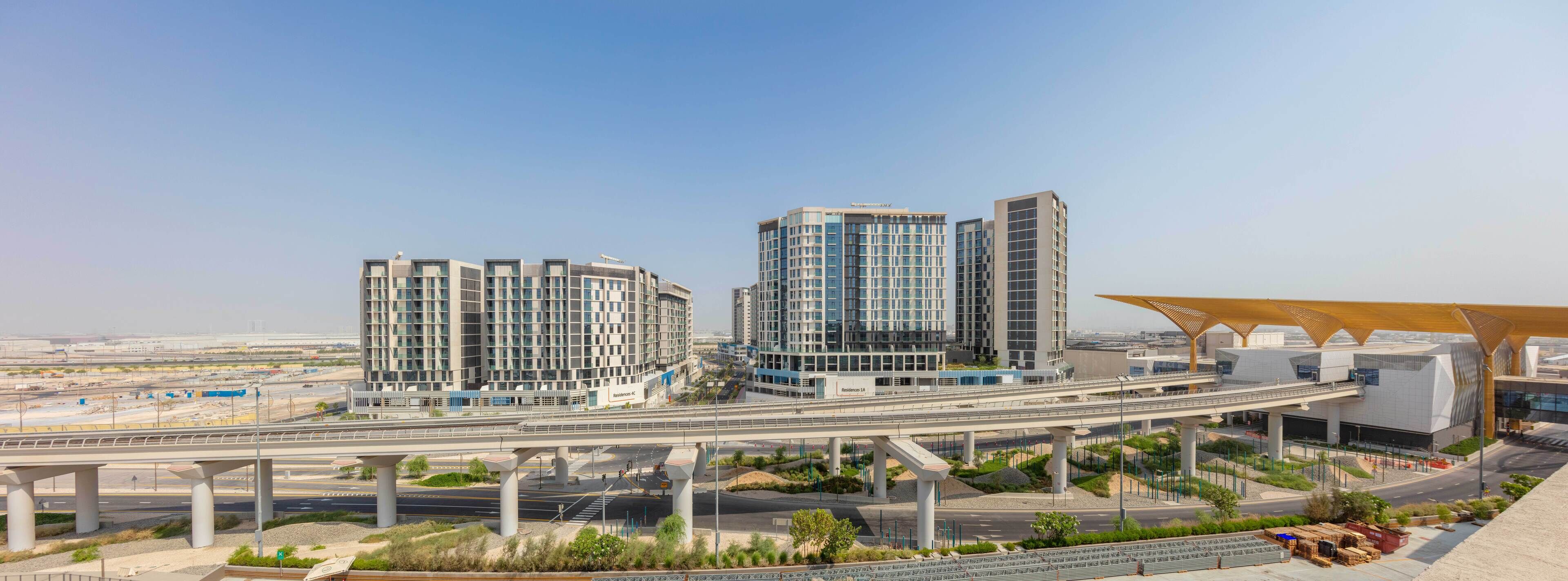 Un complexe hôtelier moderne comprenant plusieurs immeubles de grande hauteur, une galerie couverte et des espaces paysagers.