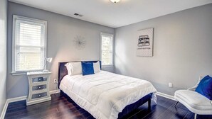 A bedroom with a bed, bedside tables, a chair, and a wall art piece. - Stone Mountain  Home  Amazing Yard & Pool (Stone Mountain)