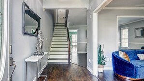 A modern interior with a wooden staircase, a blue sofa, and a statue on a console table. - Stone Mountain  Home  Amazing Yard & Pool (Stone Mountain)