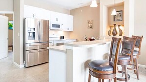 A modern kitchen with stainless steel appliances, a central island, and bar stools.