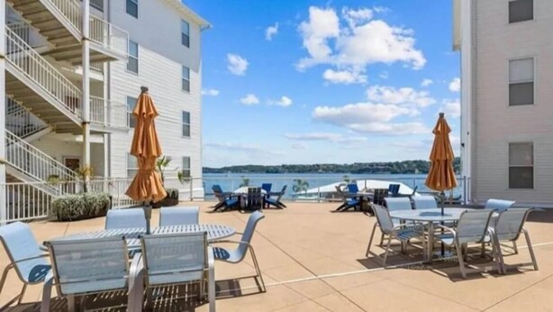 A rooftop terrace with outdoor seating, a view of the sea, and a staircase leading to an upper floor.