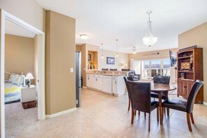 Cozy living space with a dining table, sofa, and TV, featuring a kitchen with cabinets and appliances.