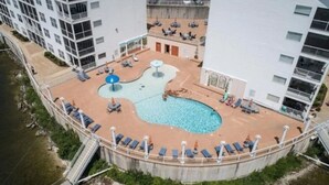 An aerial view of a hotel with a pool area, including lounge chairs and umbrellas.