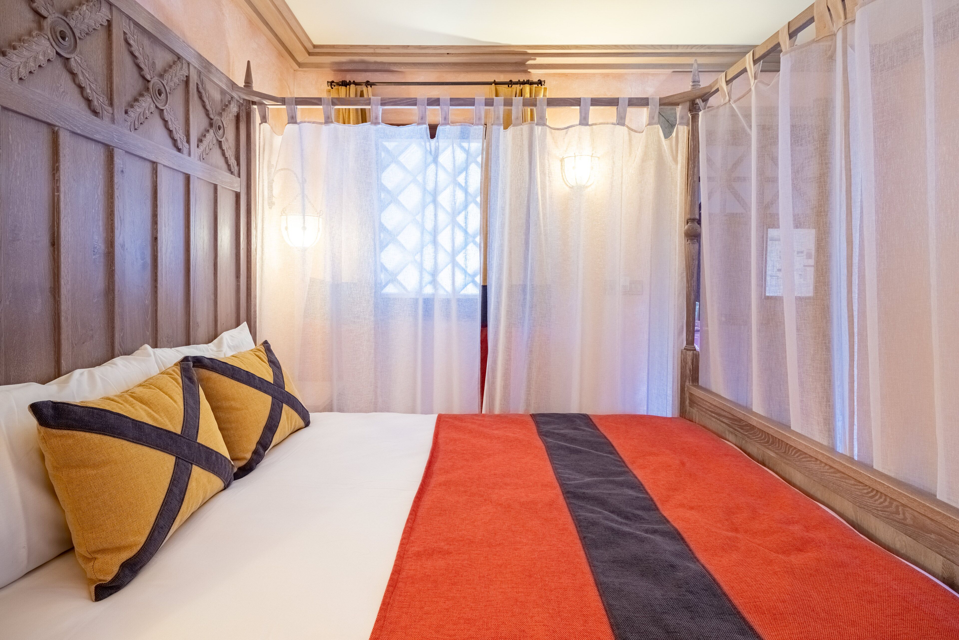 A hotel room with a bed, curtains, and a wooden headboard.