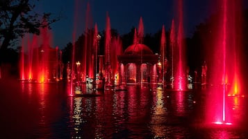 A nighttime view of a fountain with a central gazebo, surrounded by water jets.
