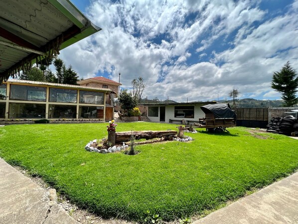 A residential property with a well-maintained lawn, a wooden deck, and a large house with multiple windows. - Estancia Jardín de Teresita (Tarqui)