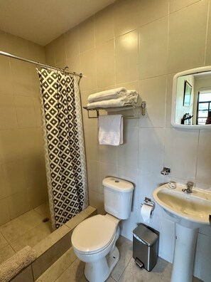 A bathroom with a shower, toilet, sink, and a towel rack. - Estancia Jardín de Teresita (Tarqui)