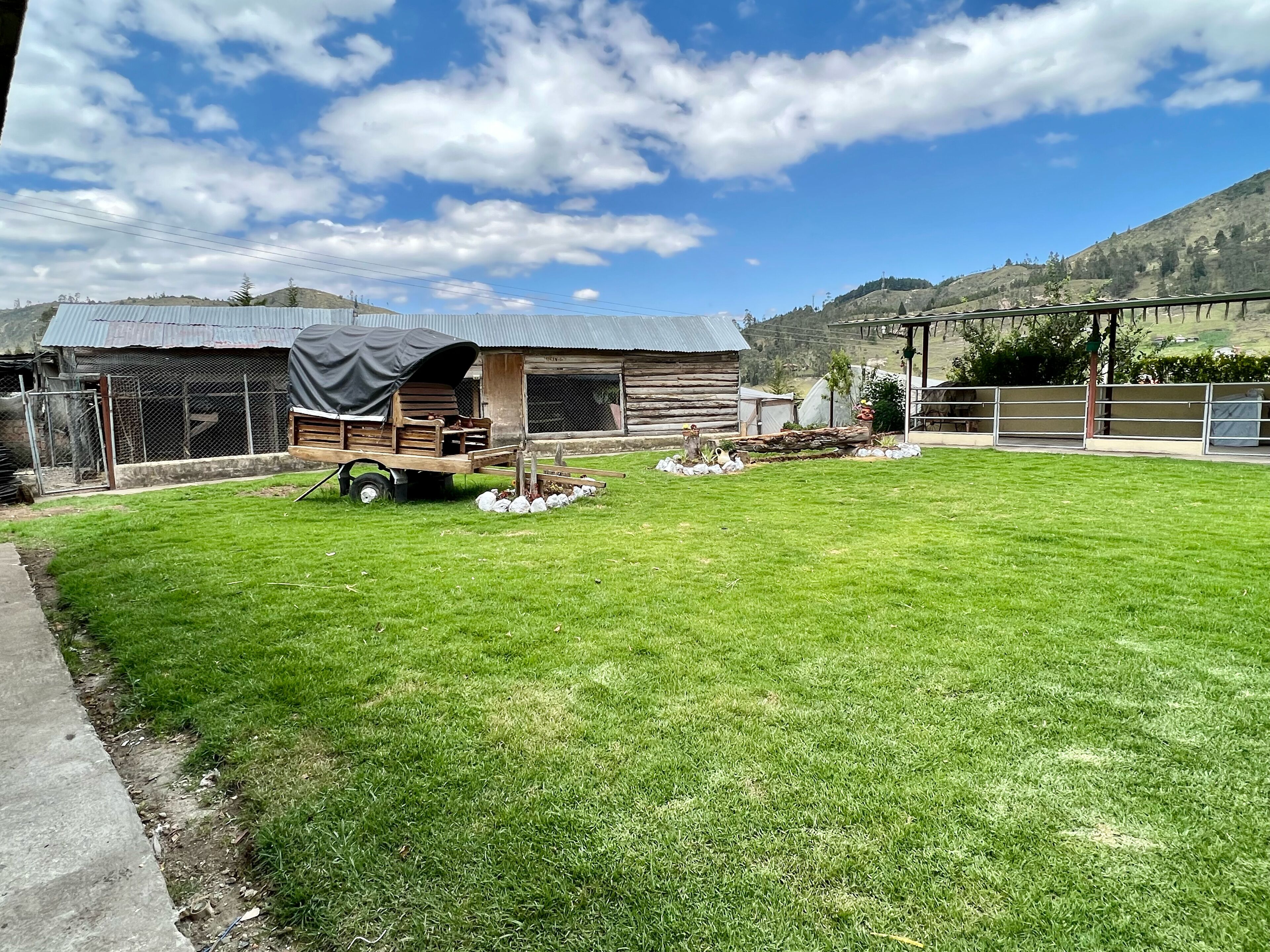 A rural farm with a fenced yard, a wooden barn, and a small tractor.