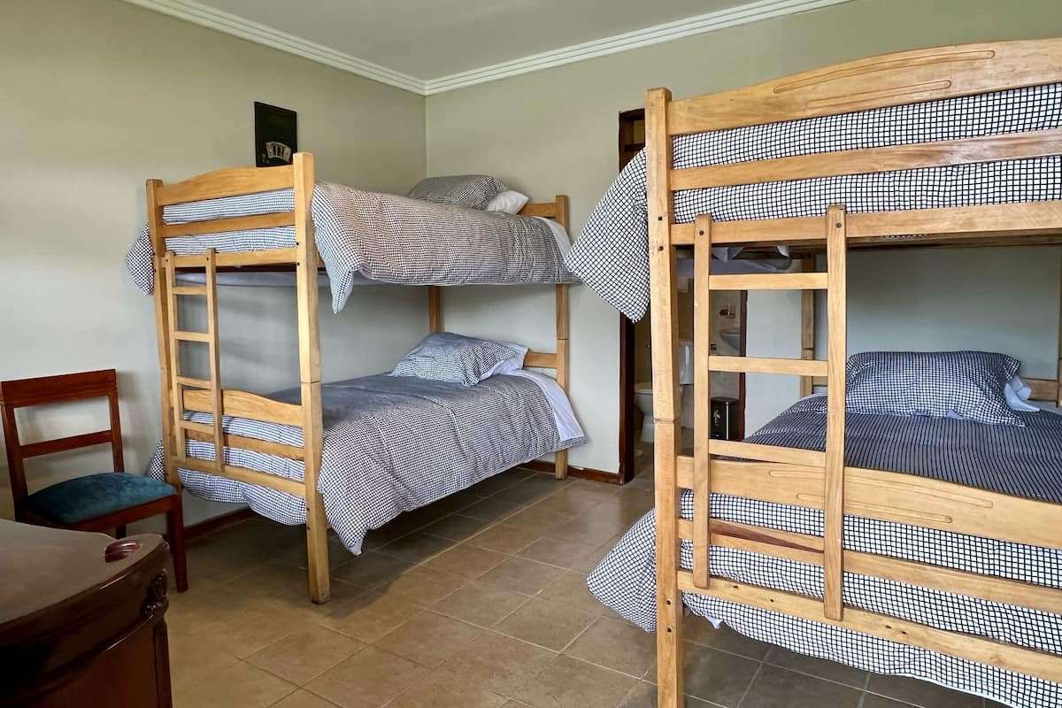 A room with two bunk beds, a wooden desk, and a chair.