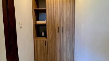 Un pasillo con un armario de madera, suelo de baldosas y una puerta a la izquierda.