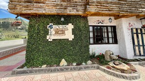 A rustic building with a wooden exterior, a sign reading "El Jardín de Teresita," and a view of the surrounding landscape.