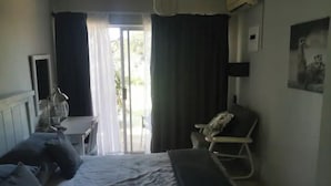 Et hotelværelse med seng, skrivebord, stol og et vindue med gardiner.