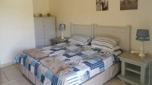 Une chambre à coucher comprenant un lit, des tables de chevet, une armoire et des œuvres d’art murales.