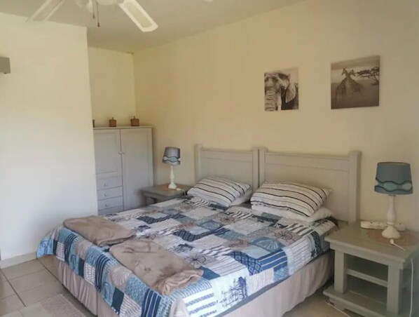 A bedroom with a bed, nightstands, a wardrobe, and wall art.