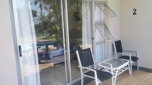 Une pièce dotée d’une porte-fenêtre coulissante donnant sur une terrasse avec une piscine et du mobilier d’extérieur.