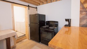 A compact kitchen with a refrigerator, stove, and coffee maker.