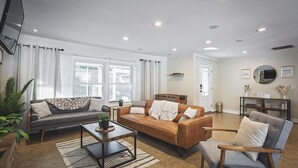 Ein Wohnzimmer mit zwei Sofas, einem Couchtisch, einem Beistelltisch, einem Sessel und einem Fernseher.