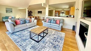Amplia sala de estar con dos sofás, una mesa de centro y una chimenea.