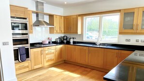 Una cocina moderna con armarios de madera, electrodomésticos de acero inoxidable y un amplio ventanal que proporciona luz natural.