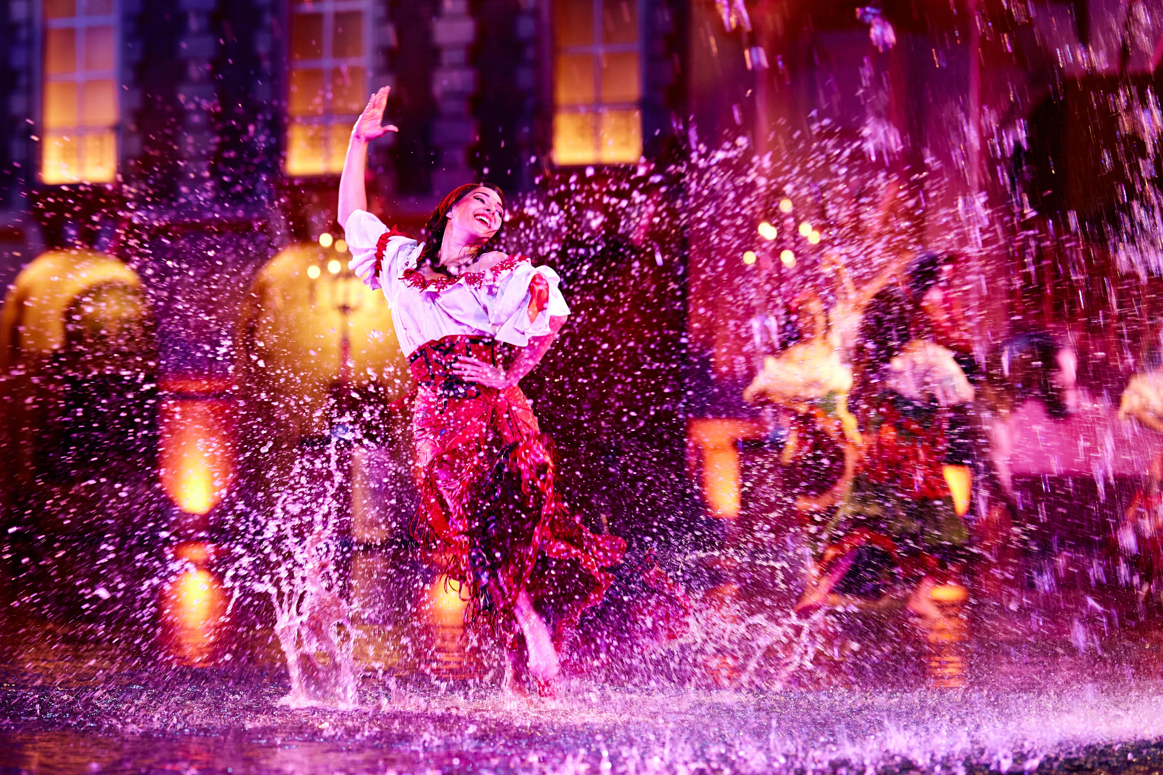 A person performing in a traditional dance with water effects.